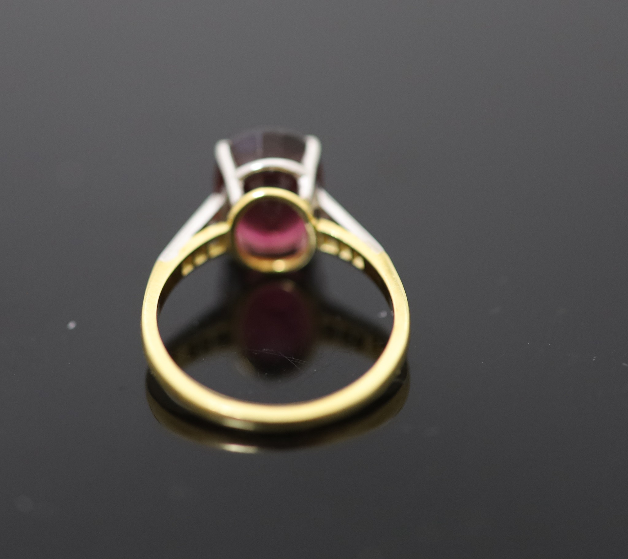 A modern 18ct gold and oval deep pink tourmaline ring, with diamond set shoulders